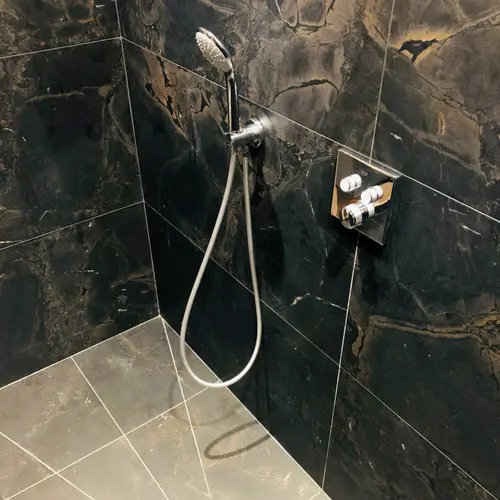 Douche encastrée avec carrelage foncé réalisée par BH Plomberie